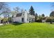 Expansive backyard with lush green lawn, patio seating, and view of the home's exterior at 6990 W 9Th Pl, Lakewood, CO 80214