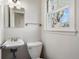 Cozy half bathroom with a pedestal sink, toilet, and a window that offers natural light at 6990 W 9Th Pl, Lakewood, CO 80214