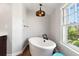 Bright bathroom features a soaking tub by a window with an elegant light fixture at 6990 W 9Th Pl, Lakewood, CO 80214