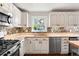 Detailed kitchen with stainless steel appliances, a colorful backsplash, and custom white cabinets at 6990 W 9Th Pl, Lakewood, CO 80214