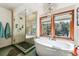 Bright bathroom features a soaking tub, walk-in shower and large windows overlooking trees at 2122 Cramner Ct, Evergreen, CO 80439