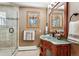 Charming bathroom with a glass shower, stylish vanity, a decorative mirror, and views through the window at 2122 Cramner Ct, Evergreen, CO 80439