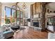 Bright living room boasts a stone fireplace, hardwood floors, and large windows with scenic views at 2122 Cramner Ct, Evergreen, CO 80439