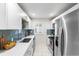 Modern kitchen featuring stainless steel appliances, quartz countertops, and a blue backsplash at 1623 Dayton St, Aurora, CO 80010