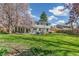 Spacious backyard view from lawn, featuring patio seating, a hot tub, and mature shade trees at 6660 E Floyd Ave, Denver, CO 80224
