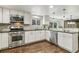 Bright kitchen featuring stainless steel appliances, white cabinetry, mosaic backsplash, and hardwood flooring at 6660 E Floyd Ave, Denver, CO 80224