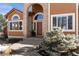 Front entrance of a two-story house with arched entryway and landscaping at 15050 Harrison St, Brighton, CO 80602