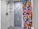 Modern walk-in shower with decorative tile, glass shelves, and a vibrant, colorful shower curtain at 4840 Point Mesa St, Castle Rock, CO 80108
