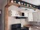 Outdated kitchen featuring a black stove and range hood, and a decorative border above the cabinets at 660 Hickory St, Hudson, CO 80642