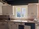 Outdated kitchen featuring white cabinets, a double basin sink, and a window overlooking the backyard at 660 Hickory St, Hudson, CO 80642