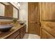 Bathroom with and vessel sinks, granite counters, dark wood cabinetry, and wood door at 11784 Spruce Mountain Rd, Larkspur, CO 80118