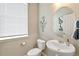 Well-lit powder room with an oval mirror, pedestal sink, and neutral décor at 3193 Belleville Ridge Rd, Elizabeth, CO 80107