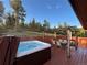 Outdoor deck featuring a hot tub and dining set with pergola, surrounded by lush greenery at 10786 Marclif Rd, Conifer, CO 80433