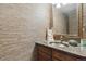 This powder room features granite counters, sink, woven wallpaper, and decorative mirror at 2783 W Long Dr # B, Littleton, CO 80120