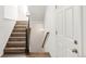 Bright staircase featuring wood-look flooring and a dark wood railing, leading to the upper level of the home at 10152 Yampa Ct, Commerce City, CO 80022