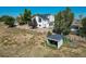 Aerial view of a property showcasing a home, horse area, and surrounding landscape with mature trees and fencing at 6242 W Lakeside Ct, Littleton, CO 80125