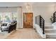 Inviting foyer featuring a wooden door, decorative chandelier, and staircase with modern railings at 6242 W Lakeside Ct, Littleton, CO 80125