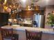 Country-style kitchen with stainless steel appliances, tiled countertops, and overhead pot rack at 14282 E Radcliff Cir, Aurora, CO 80015