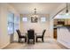 Dining room with a glass table and four chairs next to bright windows and an open view into the kitchen at 5892 W 94Th Pl, Westminster, CO 80031