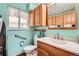 Well-lit bathroom features a toilet, wooden cabinets, a large sink, and a window with sheer curtains at 10223 W 77Th Dr, Arvada, CO 80005