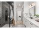 Beautiful bathroom featuring modern black fixtures, shower with hexagon tile, and long vanity with white cabinets at 16722 Shoshone St, Broomfield, CO 80023