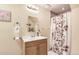 Bright bathroom with wood vanity and sink and a flower-patterned shower curtain at 4276 S Tempe Ct, Aurora, CO 80018