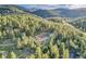 An aerial view showcasing the property surrounded by lush green trees and mountains, offering a secluded feel at 5254 Cheyenne Rd, Indian Hills, CO 80454