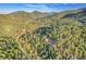 An aerial view of a home with a pool surrounded by lush trees and mountains in the background at 5254 Cheyenne Rd, Indian Hills, CO 80454