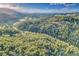 An aerial view showcasing the property's stunning natural surroundings with lush trees and mountains in the distance at 5254 Cheyenne Rd, Indian Hills, CO 80454