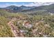 A breathtaking aerial view of a serene mountain home surrounded by lush forest and majestic mountains at 5254 Cheyenne Rd, Indian Hills, CO 80454