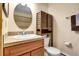 Bathroom featuring a round mirror, wooden cabinet and vanity with tile countertop at 5254 Cheyenne Rd, Indian Hills, CO 80454