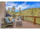 Outdoor deck with seating offers views of surrounding hillside and forest at 5254 Cheyenne Rd, Indian Hills, CO 80454