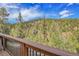 View from the deck showing lush greenery and a distant mountain range at 5254 Cheyenne Rd, Indian Hills, CO 80454