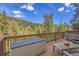 View of the spacious deck with a storage unit, hot tub, and scenic views of the surrounding forest at 5254 Cheyenne Rd, Indian Hills, CO 80454