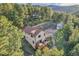 Aerial view of a home with a wraparound deck nestled in a lush forest setting near a mountain range at 5254 Cheyenne Rd, Indian Hills, CO 80454