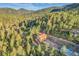 Aerial view of a rustic two story home with spacious deck surrounded by lush green trees and mountain scenery at 5254 Cheyenne Rd, Indian Hills, CO 80454
