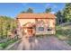 Charming two-story home with a wooden porch and gravel driveway surrounded by lush greenery and mountain scenery at 5254 Cheyenne Rd, Indian Hills, CO 80454