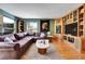 Comfortable living room featuring a leather sectional, hardwood floors, a built-in entertainment center, and natural light at 5254 Cheyenne Rd, Indian Hills, CO 80454