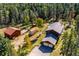 Captivating aerial view showcasing a home, detached garage, and outbuildings surrounded by lush trees at 28553 Birch Ln, Conifer, CO 80433