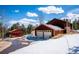 Exterior view of home featuring garage, barn and snow covered yard and blue sky at 28553 Birch Ln, Conifer, CO 80433