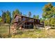 Exterior showcasing wooden deck, fenced yard, and natural landscape with mature trees at 28553 Birch Ln, Conifer, CO 80433