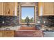 Close up view of the kitchen's copper sink and granite countertops beneath a window with a wooded view at 28553 Birch Ln, Conifer, CO 80433