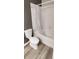 Cozy bathroom with white tile and tub with shower, featuring modern wood-style floors at 7355 S Alkire St # 203, Littleton, CO 80127