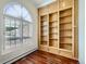 Study featuring wood floors, built in light wood bookcase, large arched window with shutter, and neutral wall color at 3810 Urban St, Wheat Ridge, CO 80033