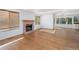 Open-concept living room with hardwood floors, a brick fireplace, and bright natural lighting from large windows at 6054 W Adriatic Pl, Lakewood, CO 80227