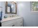 Bright bathroom features a vanity with a decorative mirror, countertop, faucet, and cabinet storage at 5944 S Yank Ct, Littleton, CO 80127