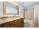 Bathroom featuring a granite vanity, large mirror, and a shower-tub combination with a floral curtain at 5944 S Yank Ct, Littleton, CO 80127