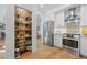 Bright kitchen with white cabinetry, stainless steel appliances, and a decorative open pantry with glass shelves at 5944 S Yank Ct, Littleton, CO 80127