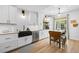 Well-lit kitchen with white cabinetry, a black farmhouse sink, stainless steel appliances, and a breakfast table at 5944 S Yank Ct, Littleton, CO 80127
