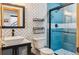 Modern bathroom with a stand-up shower, black fixtures, wood framed mirror, and white and blue tiles at 142 High Point Dr, Breckenridge, CO 80424
